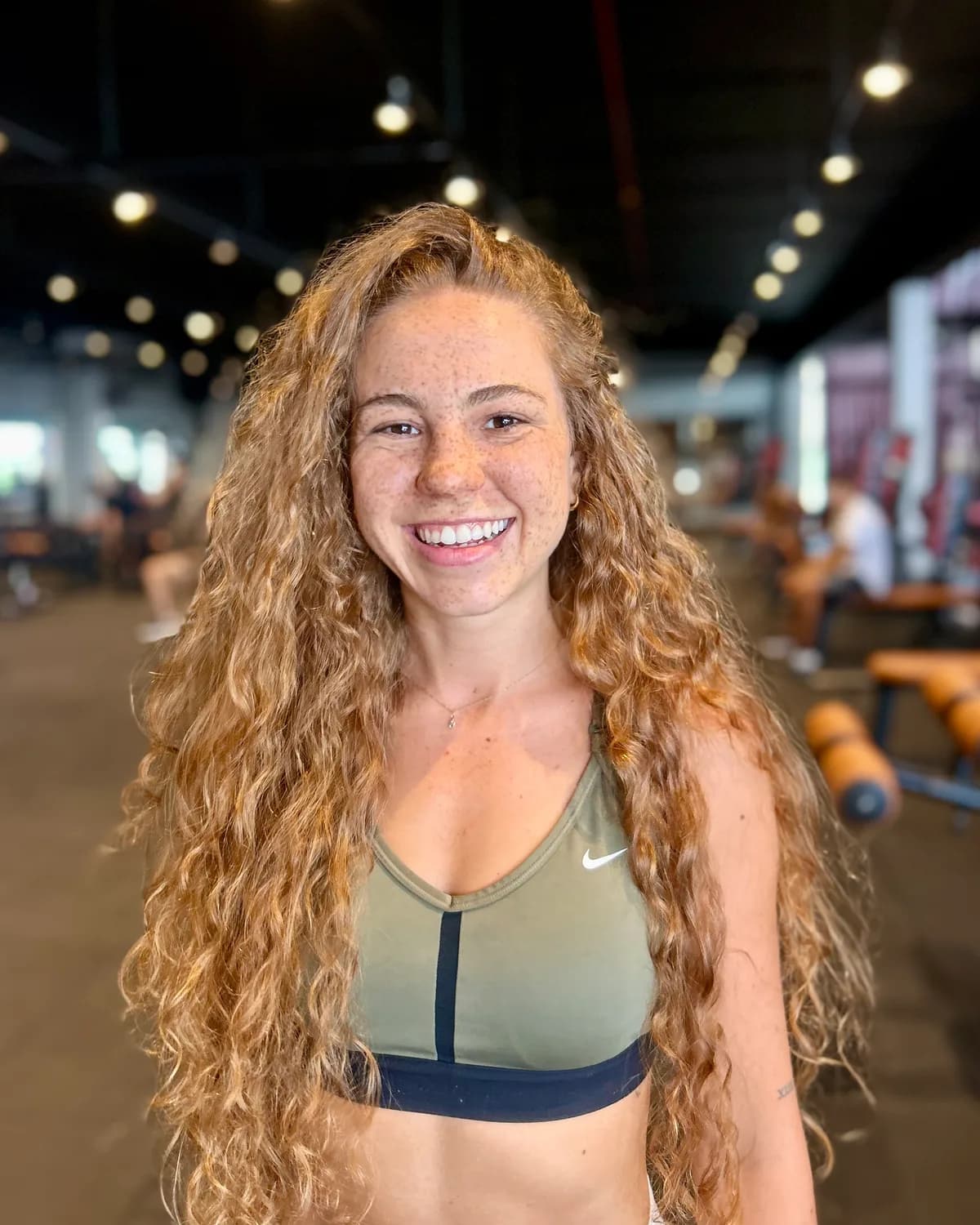 Vitória Kauer, personal trainer, sorrindo na academia